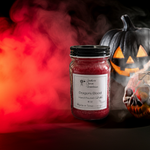 Load image into Gallery viewer, Red hand poured candle labeled 'Dragon's Blood' with Halloween-themed background including a jack-o'-lantern and skull. Southern Charm Farmhouse.
