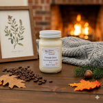 Load image into Gallery viewer, 16 oz mason Jar of 'Fireside Glow' hand poured candle on a wooden surface with a fireplace in the background.  Southern Charm Farmhouse.
