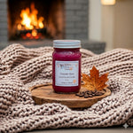 Load image into Gallery viewer, 16 oz Mason Jar of hand poured candle labeled 'Fireside Glow' on a wooden coaster with a fireplace in the background.  Southern Charm Farmhouse.
