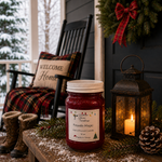 Load image into Gallery viewer, A 16 oz mason jar candle labeled 'Fireside Magic' sits on a snowy porch table beside a lit lantern, pinecone, evergreen branches, and a rocking chair with a 'Welcome Home' pillow. Southern Charm Farmhouse
