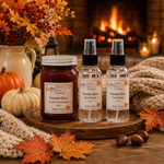Load image into Gallery viewer, Three Southern Charm Farmhouse products displayed on a wooden tray in a cozy autumn setting: a hand poured candle jar and two room spray bottles. The scene includes pumpkins, fall leaves, acorns, and a warm fireplace background.
