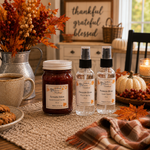 Load image into Gallery viewer, Three fall-themed home fragrance products from Southern Charm Farmhouse are displayed on a rustic table runner. The set includes a jar of Fireside Glow hand-poured candle and two spray bottles of Fireside Glow linen spray and Fireside Glow room spray, surrounded by autumn decorations like pumpkins, fall leaves, and a cozy mug.
