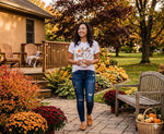 Load image into Gallery viewer, Woman in a 'hello fall' shirt standing in a garden with autumn decorations. Southern Charm Farmhouse.
