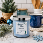 Load image into Gallery viewer, A blue hand poured 2-wick candle in a clear glass jar with a silver lid sits on a marble surface in a cozy holiday kitchen setting. The label reads ''Jack Frost'. Southern Charm Farmhouse

