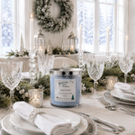 Load image into Gallery viewer, A  scented hand poured candle in a clear glass jar sits on a decorated holiday table setting. The candle wax is a pale icy blue, and the label reads 'Jack Frost' by 'Southern Charm Farmhouse'.
