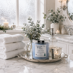 Load image into Gallery viewer, A hand poured candle labeled  'Jack Frost' holiday scented candle, styled on a silver tray with white towels, a glass pump bottle, a small candle, and eucalyptus branches in a bright, modern bathroom setting. Southern Charm Farmhouse
