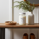 Load image into Gallery viewer, 16 oz Hand Poured Lakeside Cabin Candle, vase with greenery, and wooden bowl on a table against a white wall. Southern Charm Farmhouse.
