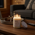 Load image into Gallery viewer, 16 oz Hand Poured Lakeside Cabin Candle in a jar on a wooden table with a cozy living room background. Southern Charm Farmhouse.
