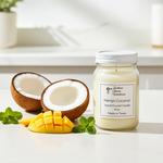 Load image into Gallery viewer, 16 oz Mason jar hand poured candle labeled 'Mango Coconut' with a split coconut and mango slices on a light surface. Southern Charm Farmhouse.
