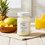 Load image into Gallery viewer, 16 oz mason Jar of Mango Coconut candle with a bowl of fruit and a glass of orange juice on a wooden surface. Southern Charm Farmhouse.

