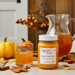 Load image into Gallery viewer, 16 oz mason Jar of mulled cider press candle with glass of mulled cider and pumpkins in the background. Southern Charm Farmhouse.

