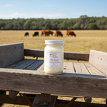 Load image into Gallery viewer, 16 oz Mason Jar of 'Open Range' hand poured candle on a wooden surface with a field and cows in the background. Southern Charm Farmhouse.
