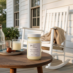Load image into Gallery viewer, 16 oz Mason Jar hand poured candle on a wooden table with a rocking chair and house in the background. Southern Charm Farmhouse.
