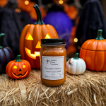 Load image into Gallery viewer, 16 oz Mason Jar of 'Pumpkin Hollow' hand poured candle on hay with Halloween-themed pumpkins in the background. Southern Charm Farmhouse.
