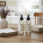Load image into Gallery viewer, One 4 oz. Room spray and One 4 oz Linen Spray bottles on a wooden table with lavender flowers in the background. Southern Charm Farmhouse.
