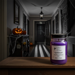 Load image into Gallery viewer, 16 oz mason jar Purple hand poured candle labeled 'Spellbound' on a wooden surface with a Halloween-themed room in the background. Southern Charm Farmhouse.
