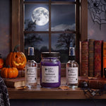 Load image into Gallery viewer, Halloween-themed products including  hand poured Spellbound candle and one room spray and one linen spray on a window sill with pumpkins and books. Southern Charm Farmhouse.
