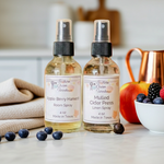 Load image into Gallery viewer, Two bottles of Southern Charm Farmhouse room and linen sprays on a table with fruits and a towel.
