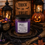 Load image into Gallery viewer, A purple wax hand poured candle in a clear glass jar with a black lid sits on a decorative tray in a Halloween-themed setting. The label reads Trick or Treat. Southern Charm Farmhouse.

