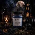 Load image into Gallery viewer, A Halloween-themed hand-poured candle by Southern Charm Farmhouse named 'Twilight Woods' in a blue glass jar, styled with a lantern, skull, and pumpkins against a spooky night background.

