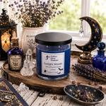 Load image into Gallery viewer, A blue hand-poured candle labeled Twilight Woods in a clear glass jar with a black lid sits on a rustic wooden tray, surrounded by witch-style decor including a moon lamp, purple flowers, crystals, and a lantern in a softly lit indoor setting. Southern Charm Farmhouse
