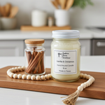 Load image into Gallery viewer, Vanilla and Cinnamon candle in a 16 oz Mason Jar on a wooden cutting board with cinnamon sticks in the background. Southern Charm Farmhouse.
