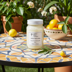 Load image into Gallery viewer, 16 oz Mason jar hand poured Candle labeled 'White Tea &amp; Sage' on a decorative table with lemons and plants in the background. Southern Charm Farmhouse
