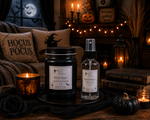 Load image into Gallery viewer, A Halloween-themed product display featuring a black jar candle and a clear spray bottle of Black Magic Spellbound Candle oil from Southern Charm Farmhouse, styled on a dark tray with lit candles, books, and witch hats in the background.
