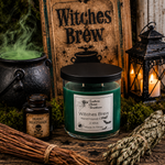 Load image into Gallery viewer, A green hand-poured candle in a clear glass jar with a black lid, labeled 'Witches Brew' by Southern Charm Farmhouse, displayed on a rustic wooden surface with Halloween-themed props including a cauldron, lantern, dried herbs, and a small bottle of 'Deadly Nightshade'.
