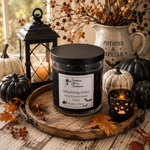 Load image into Gallery viewer, A black glass jar candle labeled ' Witching Hour' sits on a round wooden tray, styled with pumpkins, autumn leaves, a lantern, and a small starry nightlight holder in a cozy fall-themed setting. Southern Charm Farmhouse.
