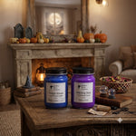 Load image into Gallery viewer, Two hand-poured candles in glass jars, one blue and one purple, labeled Twilight Woods and Witching Hour, displayed on a rustic wooden table in a cozy, Halloween-themed room with a fireplace and pumpkins in the background. Southern Charm Farmhouse
