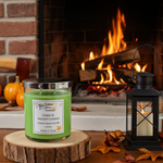 Load image into Gallery viewer, Green hand poured candle labeled 'Cedar &amp; Autumn Leaves' on a wooden stand with a lit fireplace in the background.  Southern Charm Farmhouse.
