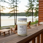 Load image into Gallery viewer, 16 oz hand poured Lakeside Cabin Candle in a jar  on a wooden deck by a lake. Southern Charm Farmhouse.
