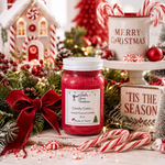 Load image into Gallery viewer, A hand-poured jar candle with a red wax fill and white label reading 'Candy Cane' by Southern Charm Farmhouse., styled on a rustic white table with candy canes, greenery, a red bow, and holiday decorations in the background.
