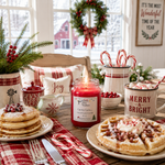 Load image into Gallery viewer, A festive holiday dining table scene with a red candle labeled 'Candy Cane' in the center, surrounded by plates of pancakes and waffles, candy canes, a mug reading 'MERRY &amp; BRIGHT,' a wreath, and a bright window in the background. Southern Charm Farmhouse.
