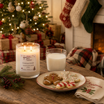 Load image into Gallery viewer, A hand-poured Christmas cookie scented candle in a clear glass jar sits on a wooden table next to a glass of milk, a plate of decorated cookies, and a folded napkin. The background is a cozy holiday scene with a lit Christmas tree, stockings, and wrapped gifts. Southern Charm Farmhouse.
