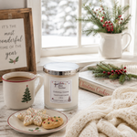 Load image into Gallery viewer, A holiday-themed handcrafted candle in a glass jar with a silver lid and a white label reading 'Christmas Cookie' by 'Southern Charm Farmhouse.' The candle is styled on a rustic table with a mug of coffee, decorated cookies, a knit blanket, a book, and a window in the background.

