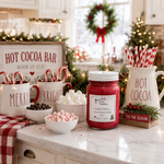 Load image into Gallery viewer, A festive hot cocoa bar setup on a kitchen counter with a red hand poured candle jar labeled 'Candy Cane' in the center, surrounded by white mugs with candy canes and marshmallows, holiday greenery, and a wreath in the background. Southern Charm Farmhouse.
