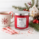 Load image into Gallery viewer, A red hand-poured candle in a clear glass jar with a silver lid sits on a white tabletop, surrounded by holiday props including candy canes, pine branches, a mug, and a small house. The front label reads 'Candy Cane'. Southern Charm Farmhouse.

