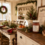 Load image into Gallery viewer, A rustic holiday table setting in a bright dining room, featuring a white and wood table with red napkins, candles, and green garlands, alongside a decorative jar candle on a wooden sideboard. Candled labeled Dickens Christmas. Southern Charm Farmhouse.


