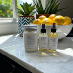 Load image into Gallery viewer, Three 4 oz Room Spray bottles and a candle on a marble surface with lemons and plants in the background. Southern Charm Farmhouse Candles.
