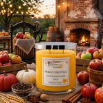 Load image into Gallery viewer, A large yellow hand poured candle in a clear glass jar with a silver lid sits on a rustic wooden table surrounded by fall-themed props including apples, cinnamon sticks, star anise, wheat, and a brick fireplace in the background. The front label reads Southern Charm Farmhouse and Mulled Cider Press.
