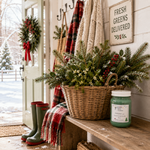 Load image into Gallery viewer, A wicker basket filled with green pine branches, evergreen foliage, and small white berries sits on a rustic wooden bench at a snowy porch. A red-and-white plaid throw blanket, green rain boots, a wreath, and a sign reading “Fresh Greens Delivered” are visible in the setting. A green hand poured candle labeled Mistletoe (type) sitting on the wooden bench. Southern Charm Farmhouse.
