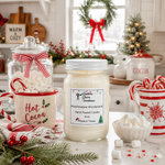 Load image into Gallery viewer, A hand-poured holiday candle in a clear glass jar with a white lid, labeled 'Marshmallow Wonderland' by Southern Charm Farmhouse, styled on a kitchen counter with hot cocoa mugs, marshmallows, and festive decorations.
