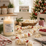 Load image into Gallery viewer, A lit hand poured candle labeled ' Marshmallow Wonderland' sits on a wooden table surrounded by holiday decorations, popcorn, red berries, twine, scissors, and a Christmas tree in the background. Southern Charm Farmhouse.
