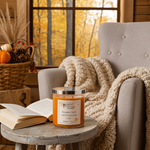 Load image into Gallery viewer, Hand Poured Candle named Pumpkin Pickin on a small table next to an open book with a cozy armchair and autumn decor in the background.  Southern Charm Farmhouse.
