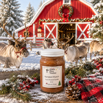 Load image into Gallery viewer, A hand poured candle jar of  Reindeer Munch stands on a rustic wooden surface in a snowy outdoor scene with red barn, reindeer, pinecones, evergreen branches, and red plaid fabric. Southern Charm Farmhouse.

