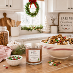 Load image into Gallery viewer, A jar candle labeled 'Reindeer Munch' sits on a wooden table in a decorated kitchen setting, surrounded by bowls of snack mix, pretzels, marshmallows, and candy. The background features holiday decorations including a wreath and a sign reading 'Baking Christmas Memories'.  Southern Charm Farmhouse
