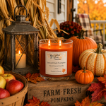 Load image into Gallery viewer, A lit spiced rum pumpkin hand poured scented candle in a clear glass jar sits on a rustic wooden crate surrounded by pumpkins, fall leaves, a lantern, and apples on a porch.  Southern Charm Farmhouse.
