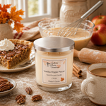 Load image into Gallery viewer, A jar hand poured candle labeled 'Vanilla Maple Pecan' by Southern Charm Farmhouse sits on a rustic tabletop surrounded by fall baking props, including a pie slice with whipped cream, pecans, cinnamon sticks, apples, a whisk, and a mug of coffee.
